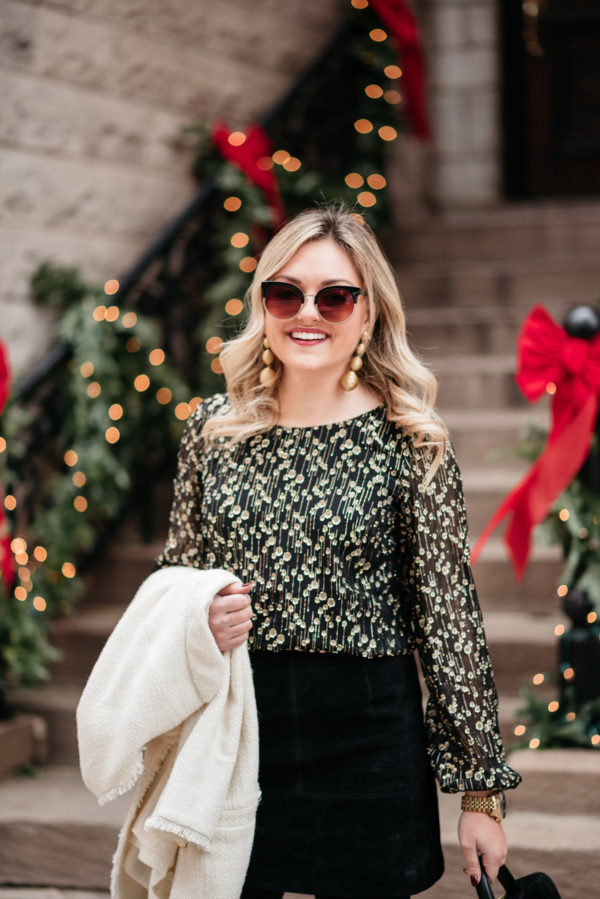 Jessica Sturdy wearing a black and gold blouse with gold earrings from Tuckernuck.