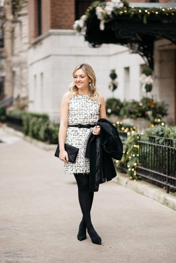 Jessica Sturdy wearing a sleeveless holiday dress from Sail to Sable with a Ralph Lauren wool coat, J.Crew tights, and Kate Spade black pumps with a black envelope clutch.