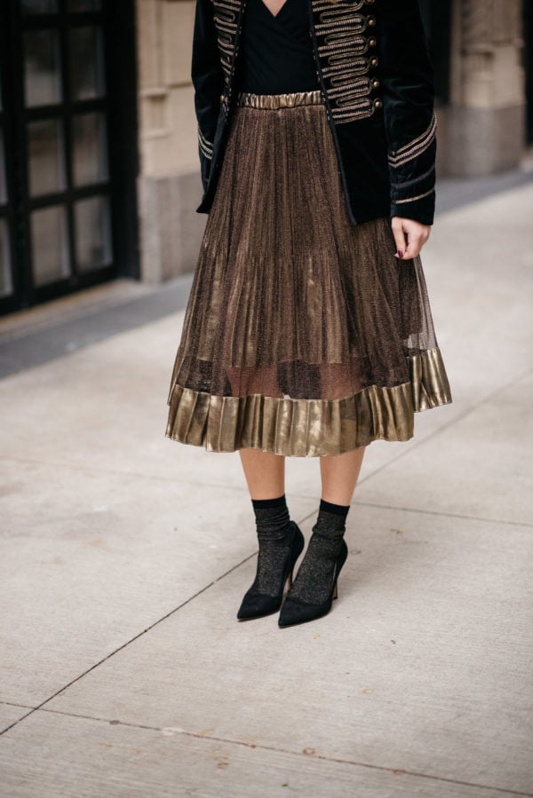 Jessica Sturdy wearing a metallic gold pleated midi skirt and Swildens black and gold shimmer socks with Kate Spade black suede Licorice pumps.