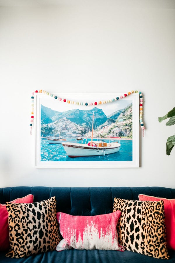 Jessica Sturdy decorating her Gray Malin living room print with a colorful garland for Christmas.
