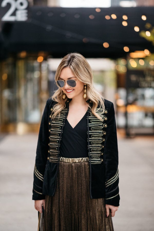 Chicago fashion blogger Jessica Sturdy wearing Ray-Ban aviators, a velvet band jacket with gold embroidery, a J.Crew bodysuit, and metallic gold pleated midi skirt with Kenneth Jay Lane gold earrings.