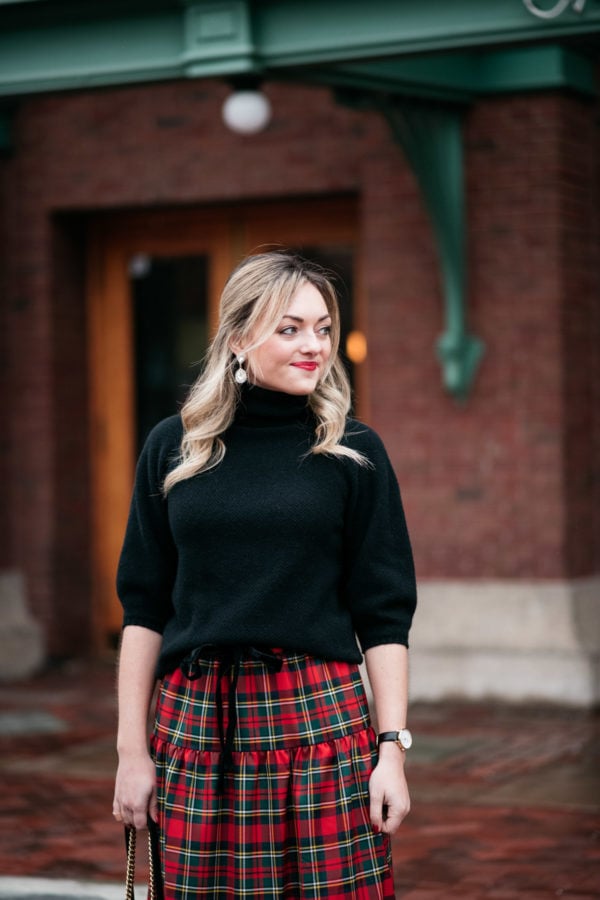 Jessica Sturdy wearing a black turtleneck, Loren Hope earrings, and a plaid skirt for a holiday party outfit.