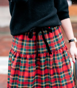 Jessica Sturdy wearing a black sweater with a tartan plaid skirt for a Christmas party outfit