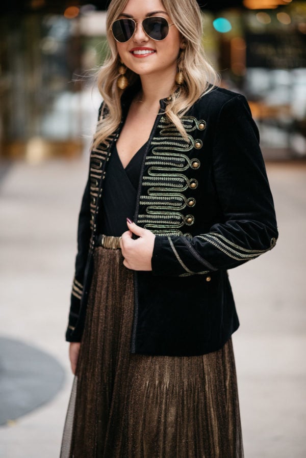 Chicago lifestyle blogger Jessica Sturdy wearing Ray-Ban aviators, a velvet band jacket with gold embroidery, a J.Crew bodysuit, and metallic gold pleated midi skirt with Kenneth Jay Lane gold earrings.