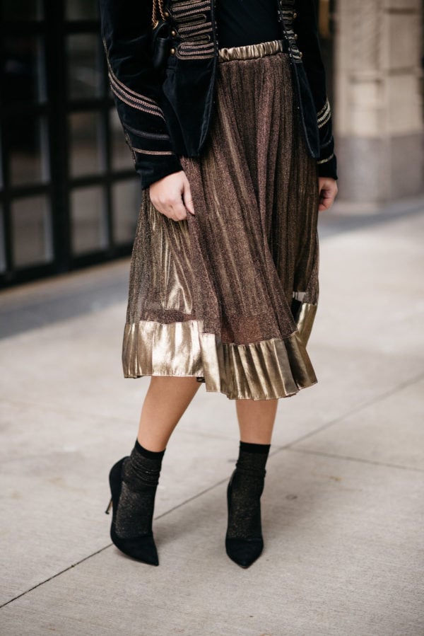 Jessica Sturdy wearing a metallic gold pleated midi skirt and Swildens black and gold shimmer socks with Kate Spade black suede Licorice pumps.