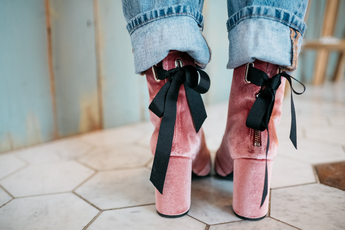 Fashion blogger Jessica Sturdy wearing pink velvet booties with a black bow and cuffed jeans.