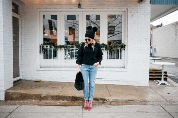 Lifestyle blogger Jessica Rose Sturdy wearing a black ruffle sleeve sweater, Levi's 501 boyfriend jeans, aviators, and pink velvet booties with a black fur bag and pom pom beanie.