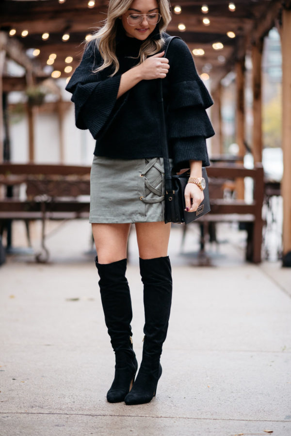 Jessica Sturdy of Bows & Sequins wearing an Endless Rose black ruffle sleeve sweater, Kensie suede lace-up skirt, and black OTK boots with a Michael Kors watch and a Lancel crossbody bag.