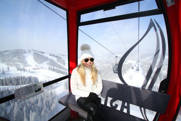 Jessica Sturdy on the Aspen Mountain Gondola wearing a fur pom beanie, cozy turtleneck sweater, leather pants, and Sorel boots.