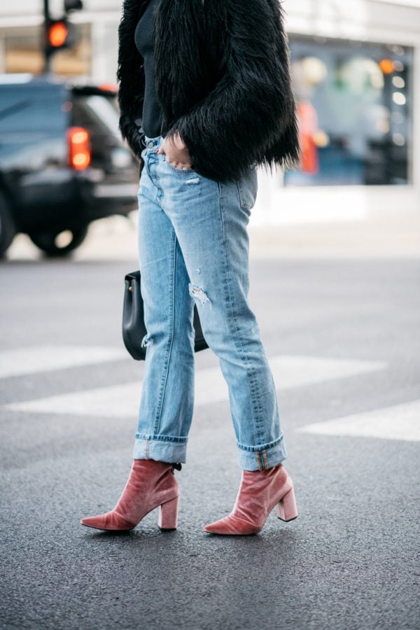Jessica Sturdy of Bows & Sequins wearing a 1.State black faux fur coat, Old Navy black ribbed sweater, Levi's 501 boyfriend jeans, and Robert Clergerie pink velvet booties with a Polene Paris top-handle bag.