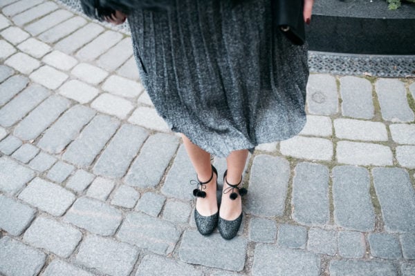 Jessica Sturdy wearing Kate Spade glitter pom-pom ankle strap heels with a silver dress.