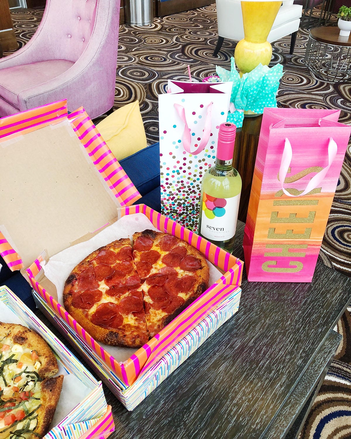 Jessica Sturdy hosts a pink-themed pizza party in Chicago with rosé, Happy Camper pizza, and colorful pizza boxes covered in wrapping paper.