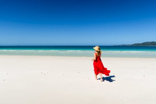 Jessica Sturdy on Whitehaven Beach in the Whitsundays in Australia wearing a ruffled red maxi dress.