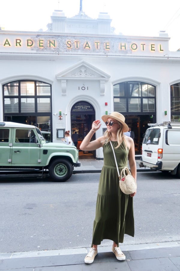 Jessica Sturdy wearing a green maxi dress and Clare V straw bag in front of Garden State Hotel bar in Melbourne Australia