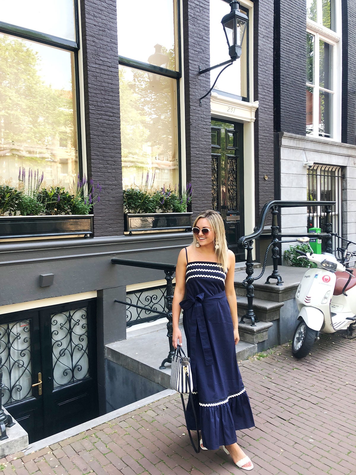 Jessica Sturdy wearing a Vineyard Vines navy blue ric rac maxi dress in front of a greystone on the canals of Amsterdam.