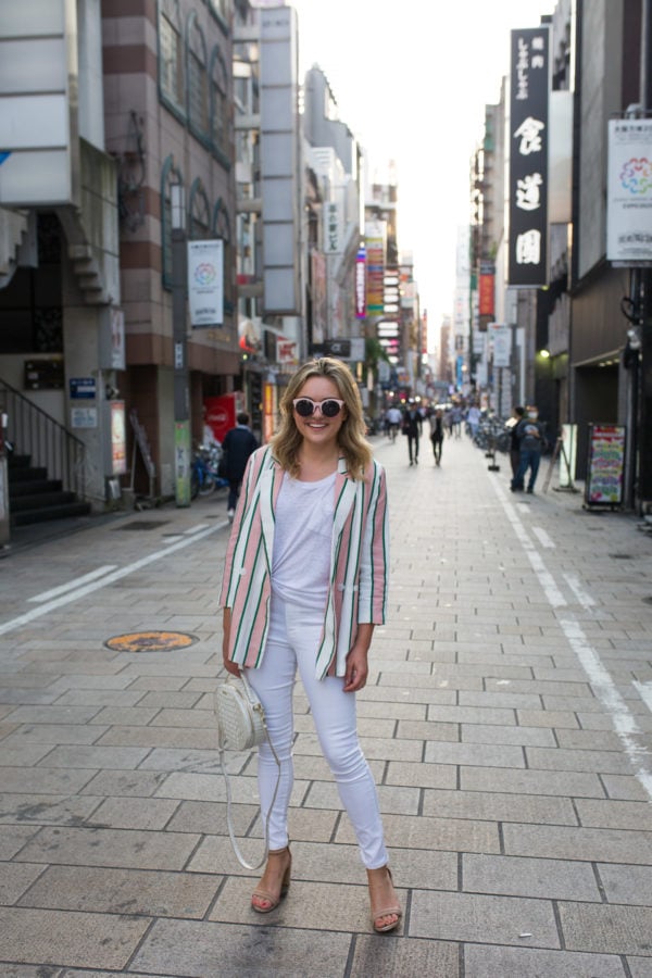 Fashion blogger Jessica Sturdy wearing a pink and white striped blazer with white jeans in Osaka, Japan.