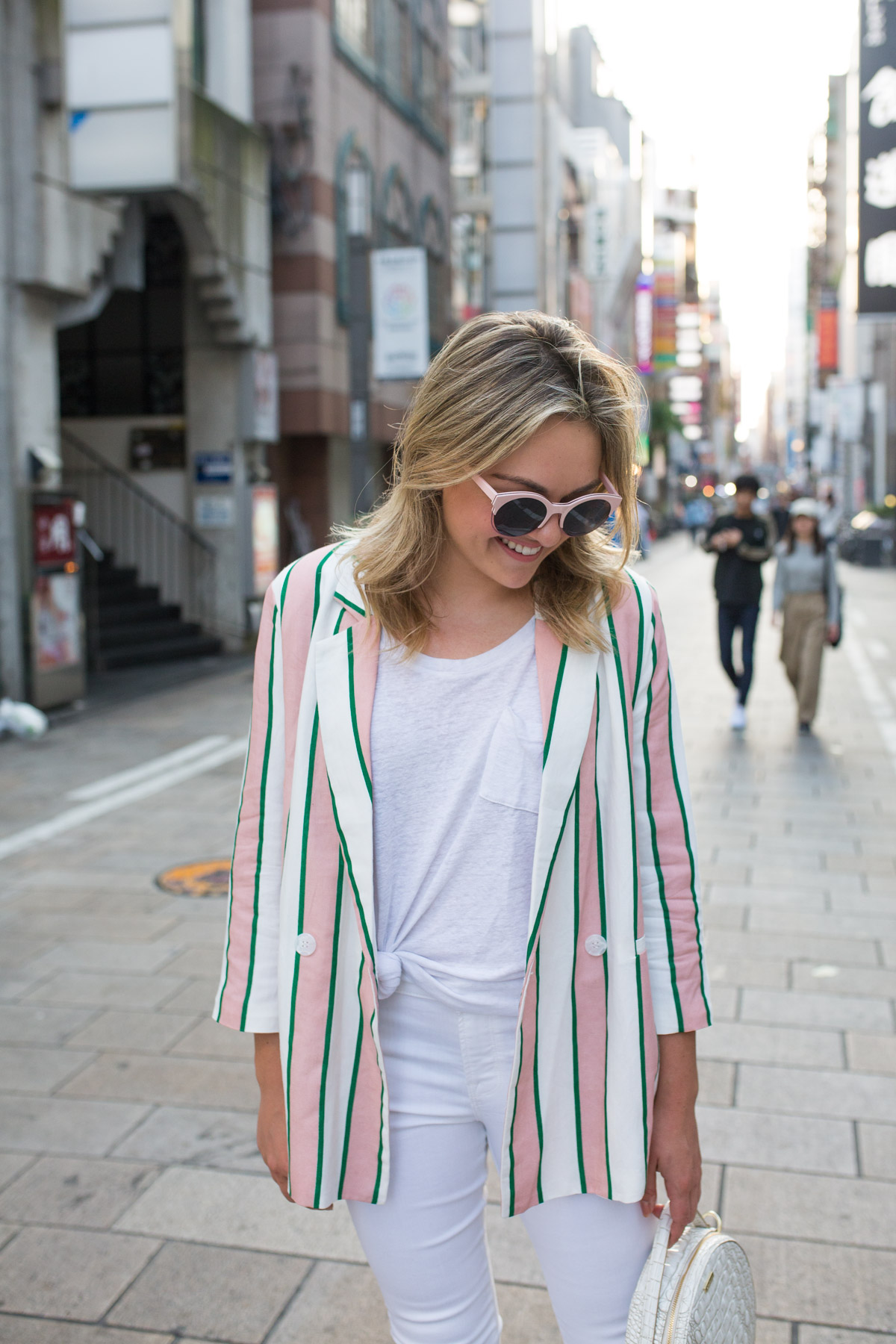 Travel Blogger Jessica Sturdy styling a pink and white oversized blazer with a knotted white tee and white jeans.