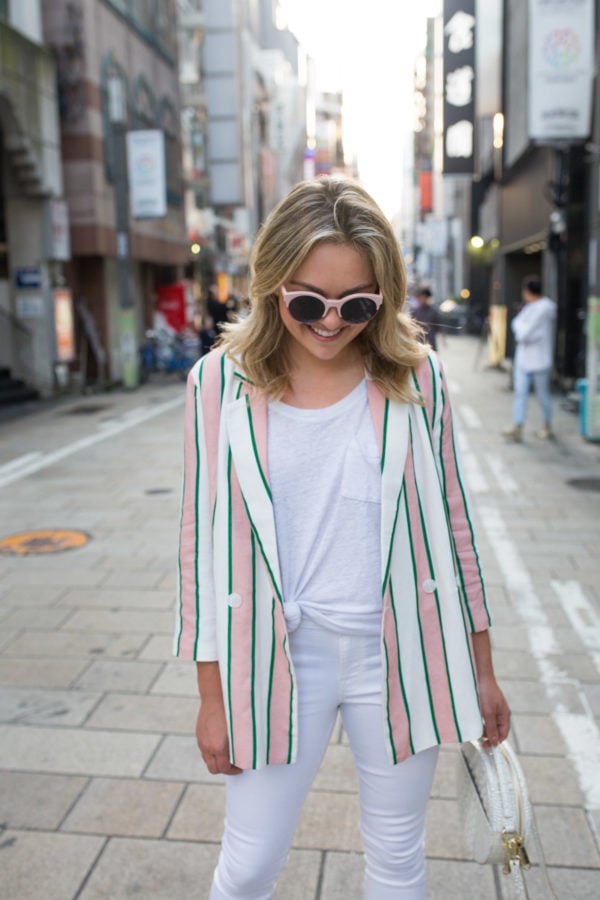 Lifestyle blogger Jessica Sturdy wearing a pink and white striped blazer with a white tee and white jeans in Japan.