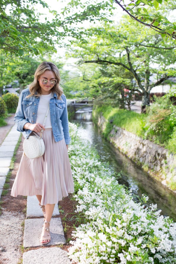 Jessica Sturdy on Philosopher's Path in Kyoto, Japan wearing a denim jacket and pleated pink midi skirt.