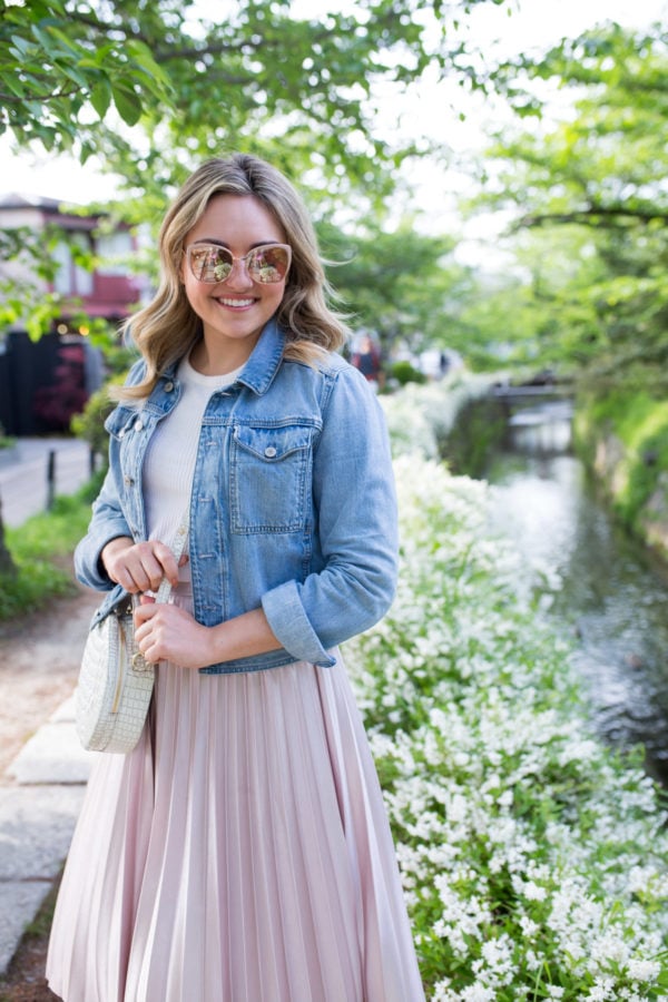 Chicago-based fashion influencer Jessica Sturdy wearing a denim jacket and rose gold sunglasses along the Philosopher's Path in Kyoto, Japan.