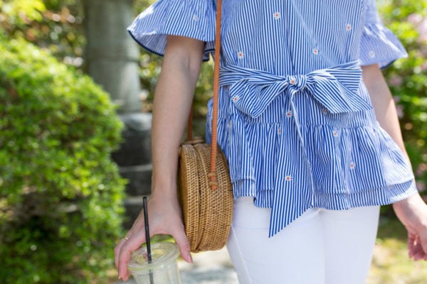 Fashion blogger Jessica Sturdy wearing a striped blue and white top with a bow tie and a circle rattan wicker bag.