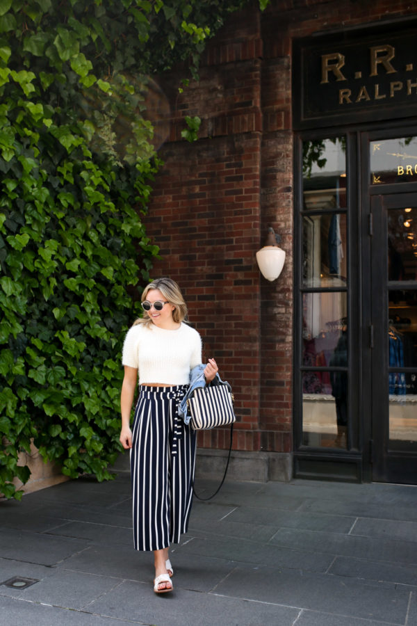 Blogger Jessica Sturdy wearing a cream short-sleeved sweater and striped wide leg pants in front of Ralph Lauren in Japan.