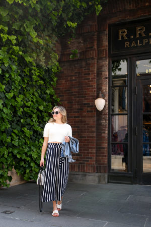 Jessica Sturdy wearing Prive Revaux sunglasses and Zara striped pants in front of Ralph Lauren in Tokyo.
