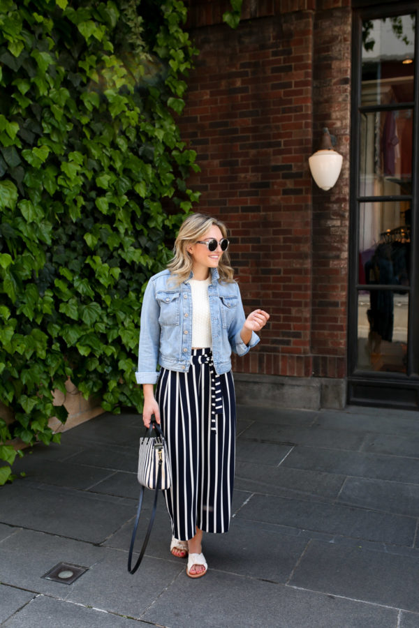 Jessica Sturdy wearing a cropped denim jacket with striped wide leg pants from Zara and a Clare V striped tote in Tokyo, Japan in front of the Ralph Lauren store.