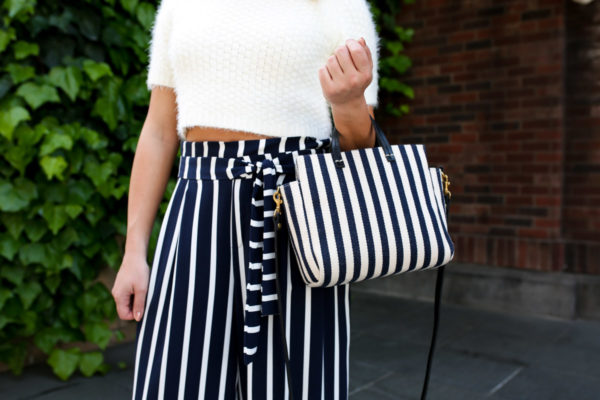 Jessica Sturdy wearing a textured crop top sweater with blue and white high-waisted pants and a Clare V stripe tote.