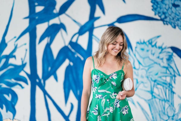Chicago lifestyle and fashion influencer Jessica Sturdy wearing a green floral dress in front of a blue and white street art mural at Ping Tom Park.