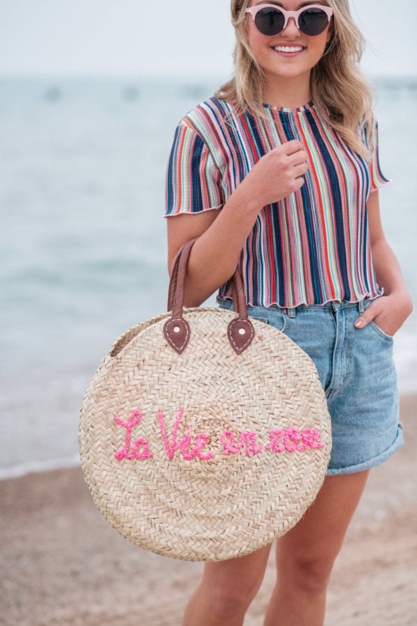 Jessica Sturdy wearing a Bershka striped ruffled hem cropped top with Cotton On high-rise flashback shorts with a "La Vie en Rose" embroidered straw tote created in collaboration with Jessica Sturdy.