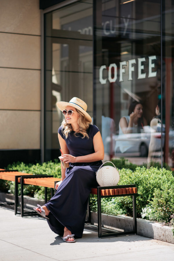 Chicago personal shopper Jessica Sturdy wearing a navy blue maxi dress with a striped straw hat, white circle bag by Brahmin, blue and white printed bow slides from J.Crew.