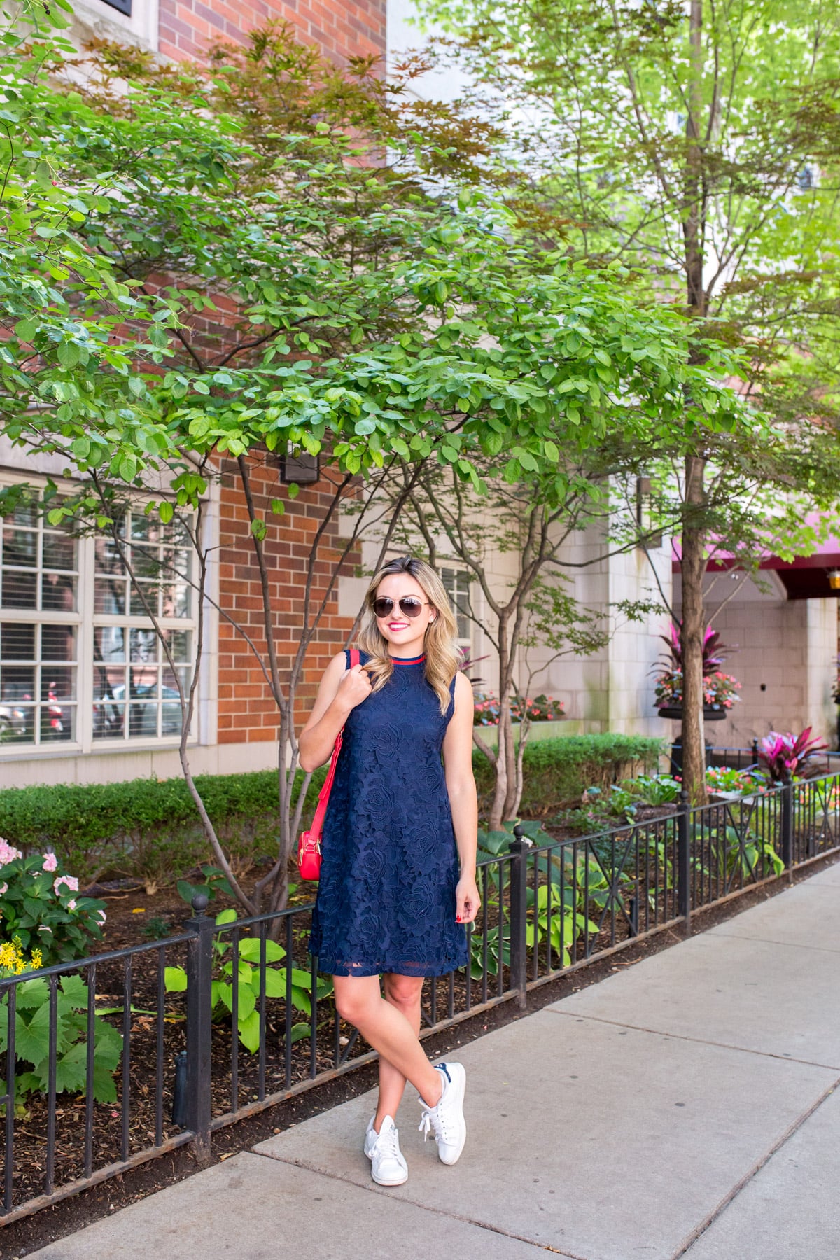 Chicago fashion blogger Jessica Sturdy wearing a navy blue lace dress with white Stan Smith sneakers in the Gold Coast.