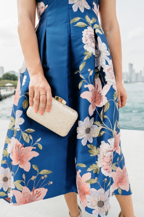 Bows & Sequins wearing a floral fit and flare dress by Eliza J with a pretty gold clutch from Nordstrom.