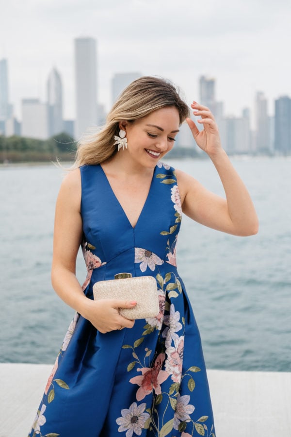 Chicago fashion blogger Bows & Sequins wearing a floral Eliza J dress with a gold clutch and white floral earrings from Lele Sadoughi.