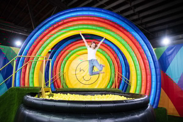 Chicago blogger Jessica Sturdy jumping into a rainbow ball pit at Happy Place