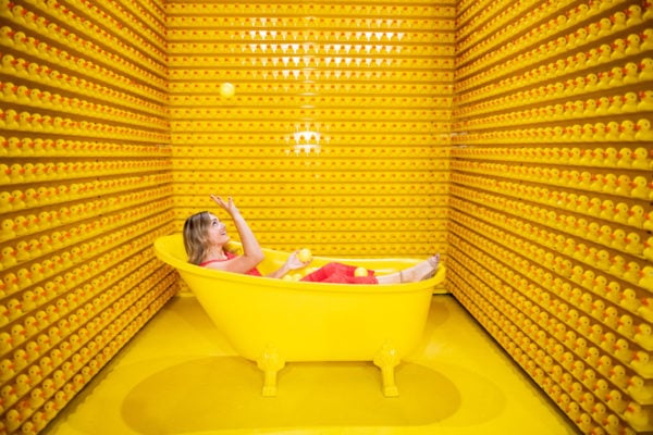 Chicago blogger Jessica Sturdy wearing an orange maxi dress in a yellow bathtub at Happy Place Chicago.