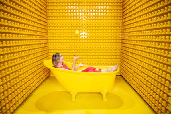 Jessica Sturdy juggling with rubber ducks in a yellow bathtub at Happy Place in Chicago.