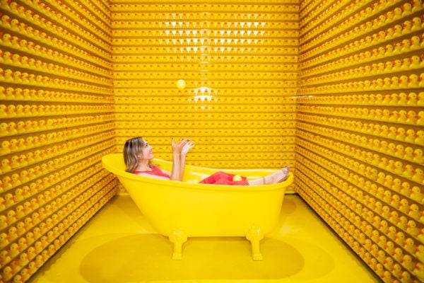 Chicago blogger Jessica Sturdy juggling yellow balls in a bathtub with rubber ducks at Happy Place