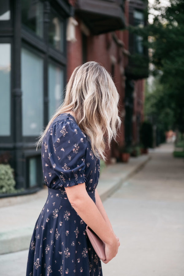 Jessica Sturdy with rooty ombre blonde hair with loose waves wearing a blue floral dress.
