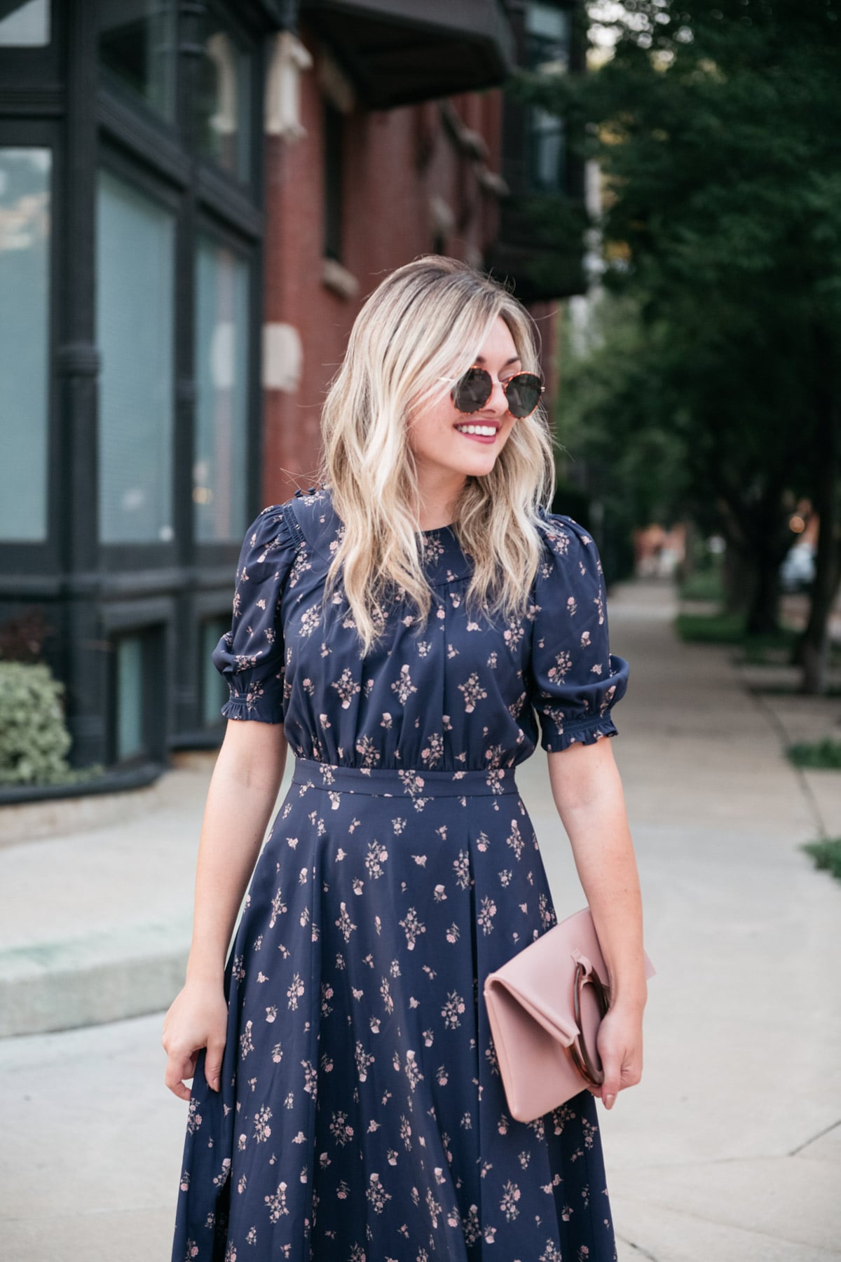 Bows & Sequins wearing a blue and pink floral dress by Gal Meets Glam with a Topshop foldover clutch and round tortoise sunglasses.
