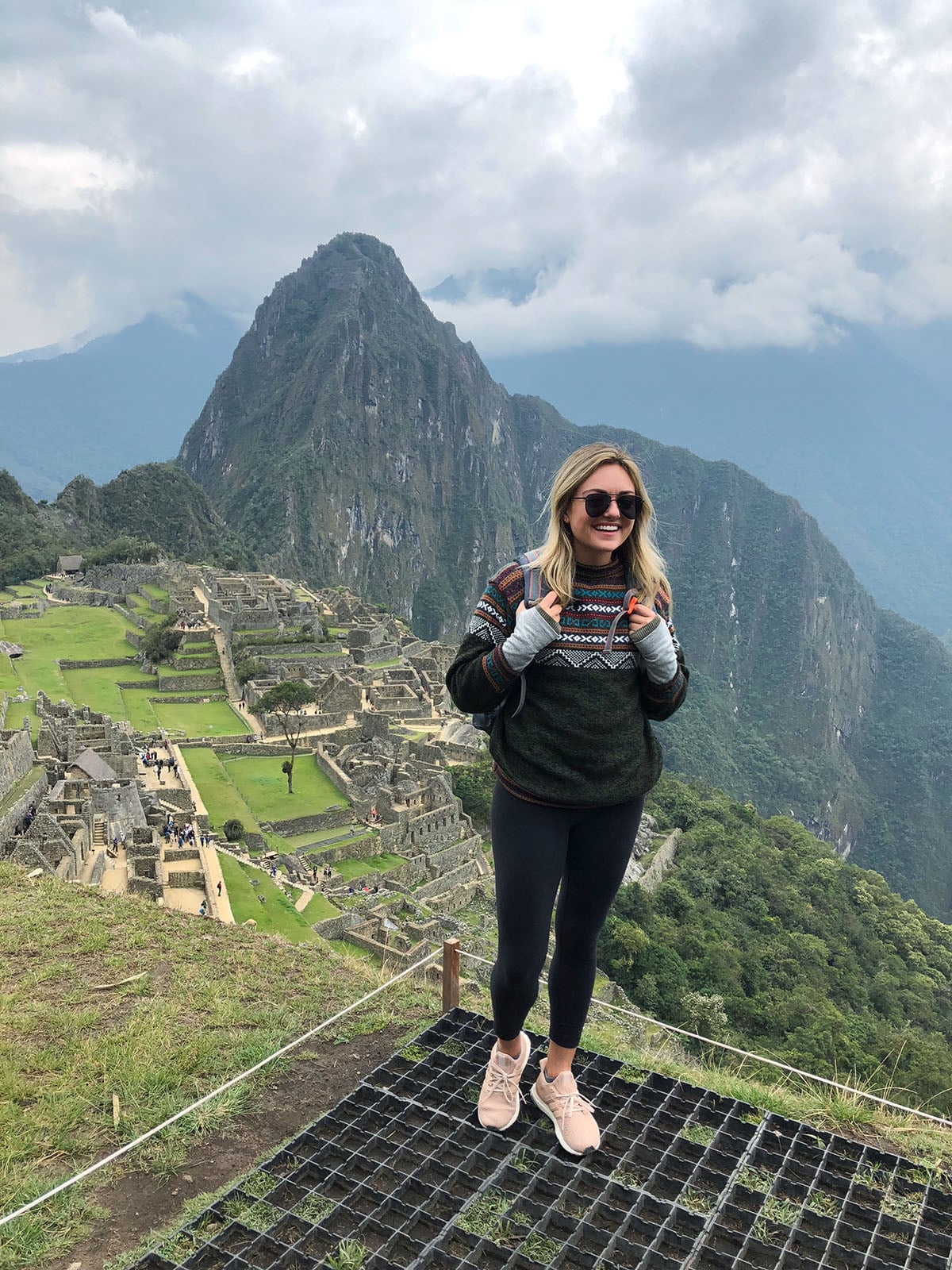 Jessica Sturdy at Machu Picchu in Peru wearing a Peruvian alpaca sweater, Lululemon leggings, Le Specs Prince aviators in matte black, and adidas Ultra Boost sneakers.