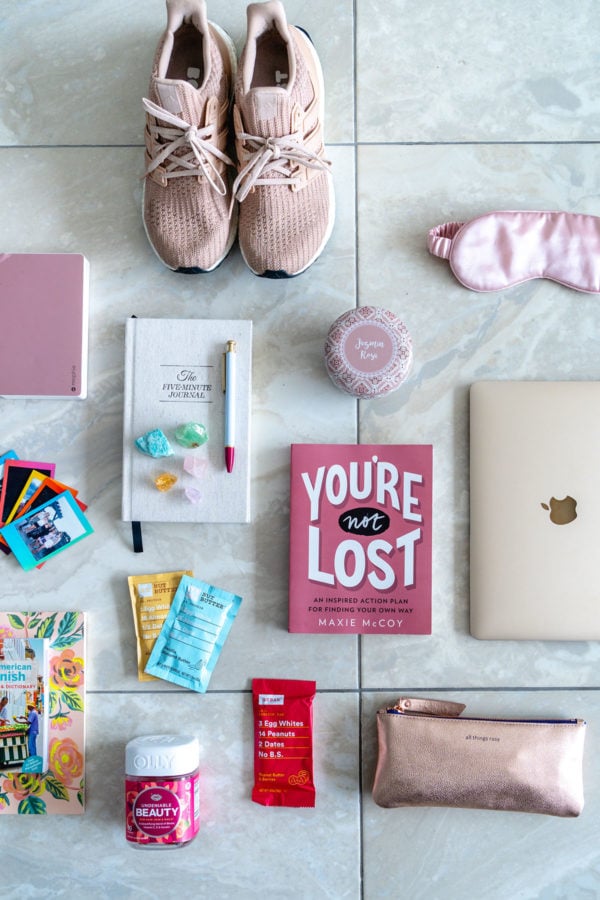 Health and wellness blogger Jessica Sturdy of Bows & Sequins shares a few of her favorite items that she packed for Remote Year: You're Not Lost book by Maxie McCoy, blush pink adidas Ultra Boost sneakers, a rose candle, a rose gold Mophie phone charger, a gold MacBook, a millennial pink eye mask, the 5 Minute Journal, and RXBar's new Peanut Butter & Jelly flavor, and more.