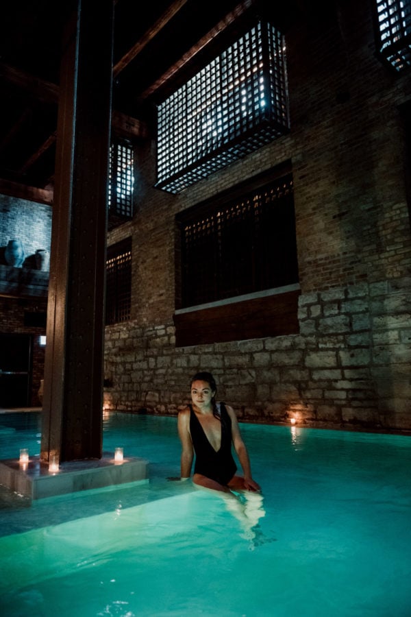 Lifestyle blogger Jessica Sturdy wearing a black one piece swimsuit at AIRE Ancient Baths in Chicago.