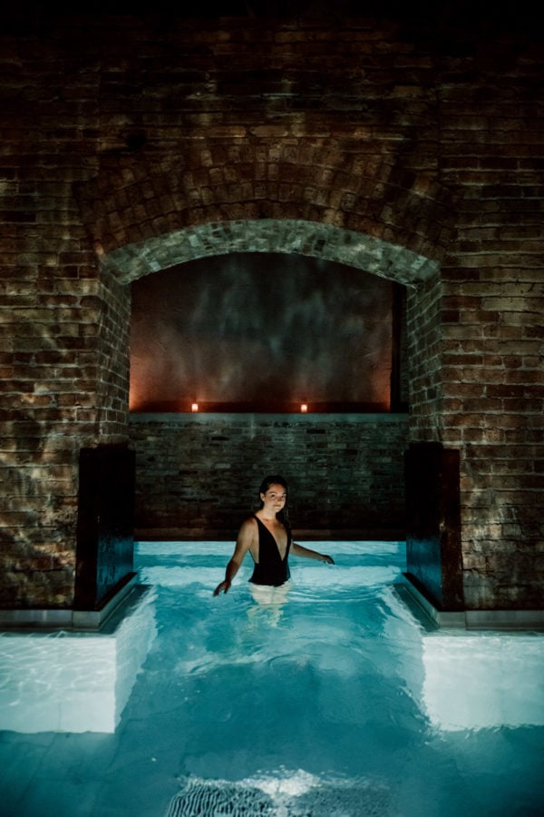 Jessica Sturdy wearing a low cut black swimsuit at AIRE Ancient Baths in Chicago