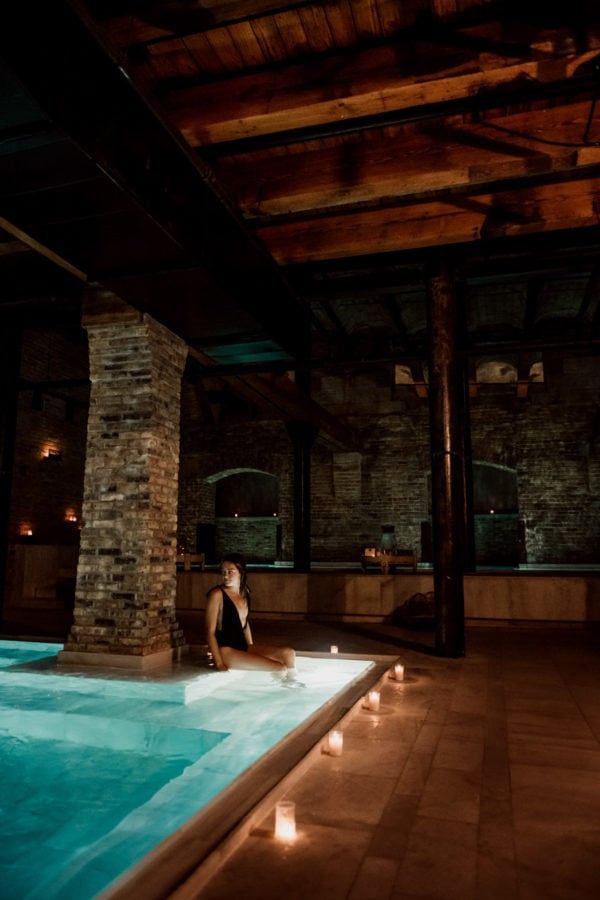 Blogger Jessica Sturdy of Bows & Sequins relaxing at AIRE Ancient Baths in Chicago in a black swimsuit.