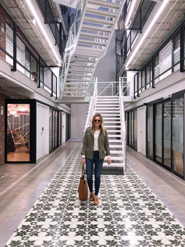 Women's lifestyle blogger Jessica Sturdy of Bows & Sequins at Comunal Coworking Barranco in Lima, Peru. She's wearing an olive green jacket, cream sweater, Frame skinny jeans, and leather slip-on loafers with a Cuyana leather tote.