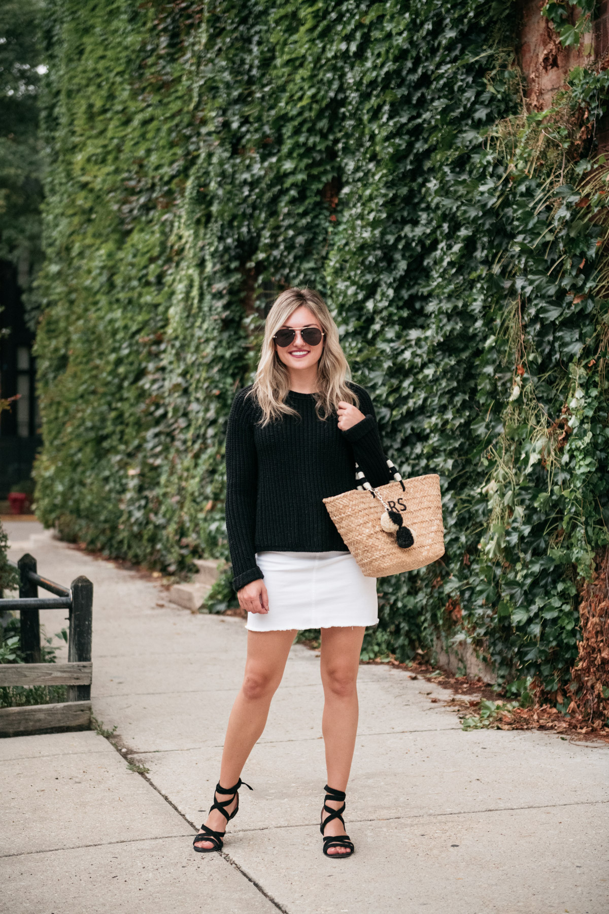 Chicago personal stylist Jessica Sturdy wearing a white denim skirt with black accessories and a straw bag.