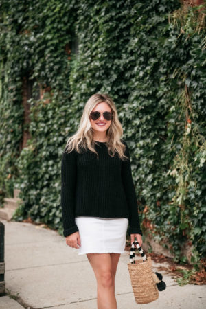 Chicago travel blogger Jessica Sturdy of Bows & Sequins styling a black sweater with a white skirt for a cute fall outfit.
