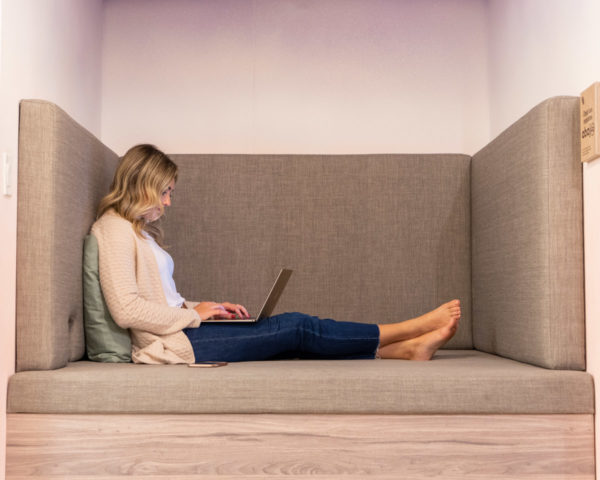 Lifestyle influencer Jessica Sturdy reflects on her time doing Remote Year. She is sitting in a cozy breakout space at Comunal Co-Working space in Lima, Peru wearing a cashmere cardigan, blue jeans, and looking at her laptop.